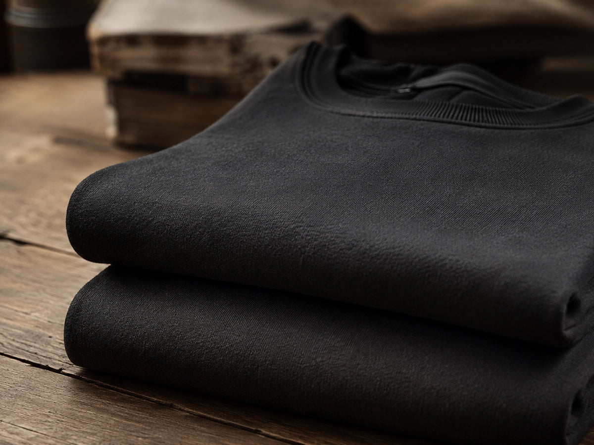 Stack of black shirts on a wooden surface